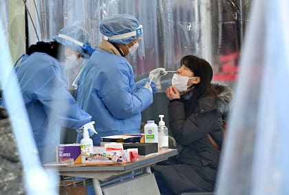 Una trabajadora médica toma una muestra de hisopado nasal de una mujer en un centro de pruebas del coronavirus en Seúl, el 16 de febrero de 2022, después de que las infecciones diarias en Corea del Sur aumentaran bruscamente hasta alcanzar un nuevo máximo de más de 90.000. 