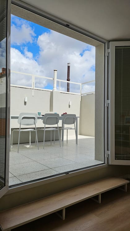 Una transición difícil se resolvió con un escalón que parece un banco. Mesa y sillas de chapa color tiza (Estudio Te).