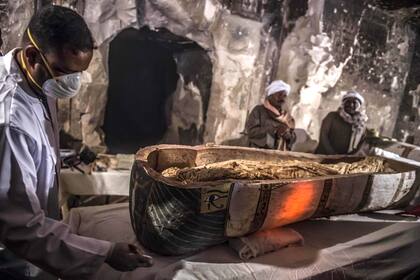 Arqueólogos egipcios inspeccionan un sarcófago intacto abierto que contiene una momia envuelta en lino y bien conservada de una mujer llamada "Thuya" 