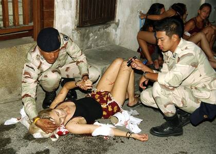 Una turista extranjera recibe la asistencia de dos soldados tras una explosión en Hua Hin, al sudeste de Bangkok