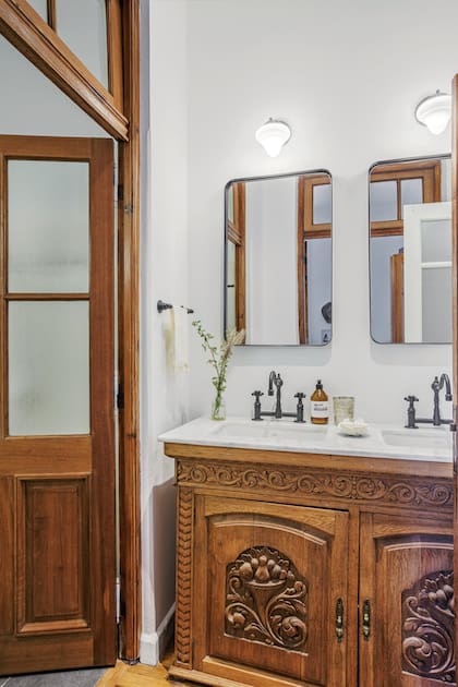 Una variante más ornamental, a la que se le agregó una tapa de mármol de Carrara y grifería de inspiración antigua en contraste con los espejos de corte moderno