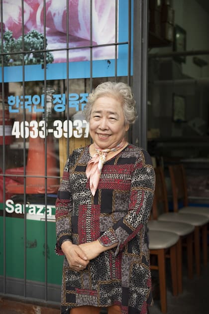 Una vecina histórica del barrio sonríe en la puerta de un local de comida