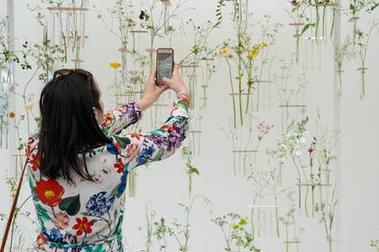 Una visitante toma una fotografía de una exhibición floral en el Gran Pabellón.