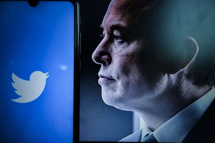 Una vista del logotipo de la empresa estadounidense de redes sociales Twitter en la pantalla de un smartphone junto a un Retrato del empresario Elon Musk, 25 de abril de 2022