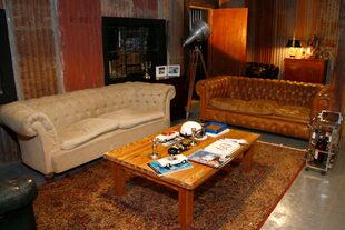 Una vista del museo recién inaugurado. Tiene, en su inmenso living, una mesa ratona de pinotea y, alrededor, dos sofás chester: uno color arena de corderoy y otro, marrón suela. 
