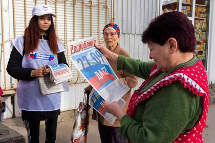 Una voluntaria de la comisión electoral regional de Luhansk distribuye periódicos a los ciudadanos locales antes de un referéndum en Luhansk, República Popular de Luhansk controlada por los separatistas respaldados por Rusia, este de Ucrania, el jueves 22 de septiembre de 2022. 