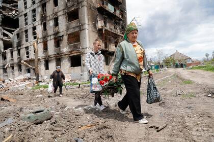 Unas mujeres pasan por delante de un edificio de apartamentos destruido en Mariupol, en el territorio bajo el gobierno de la República Popular de Donetsk, en el este de Ucrania, el lunes 2 de mayo de 2022.