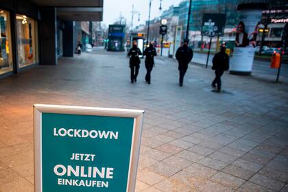 Unas personas pasan frente a una tienda por departamentos cerrada en el bulevar Kurfuerstendamm en Berlín, que promueve con un anuncio las compras online
