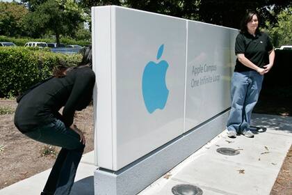 Unas turistas posan ante el cartel de la sede de Apple en Cupertino, California. La compañía se caracteriza por una comunicación institucional muy reservada