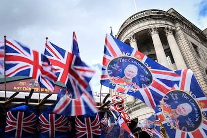 Union Jack flags and flags picturing Britain's King Charles III flap in the air as they are displayed at a street souvenirs vendor stall, in Trafalgar Square, central London, on May 5, 2023, ahead of the coronation weekend. - The country prepares for the coronation of Britain's King Charles III and his wife Britain's Camilla, Queen Consort on May 6, 2023. (Photo by SEBASTIEN BOZON / AFP)