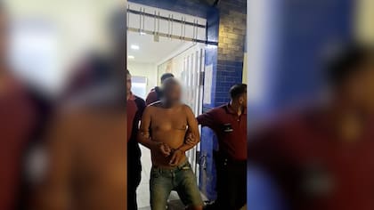 Uno de los detenidos escoltado por efectivos policiales tras el operativo que frustró la toma ilegal en La Boca