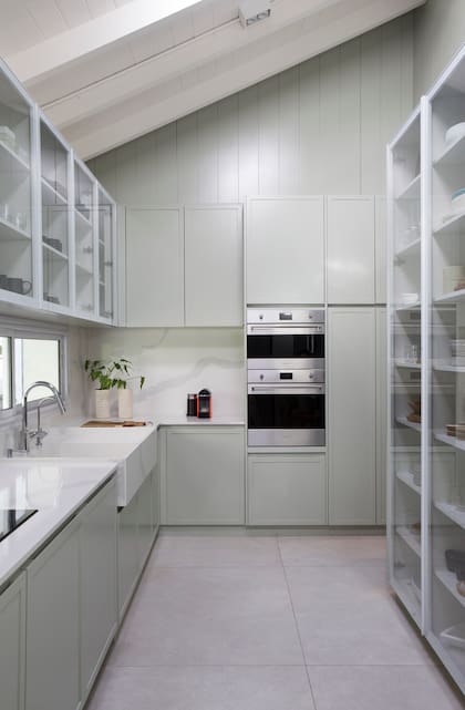 Uno de los pedidos de la dueña de casa fue más espacio de guardado en la cocina. Para aprovechar al máximo las paredes, el Estudio diseñó estanterías livianas en hierro blanco y alacenas con puertas de vidrio.