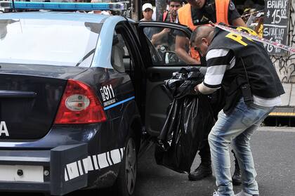 Uno de los peritos policiales lleva en una bolsa el torso hallado en un contenedor de Sarandí 270