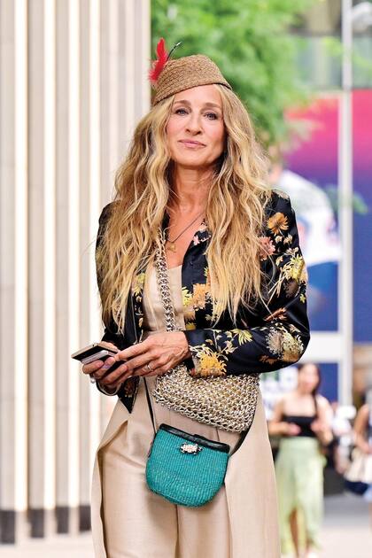 Uno de los primeros equipos que se le vieron por estos días en el rodaje, en Nueva York: mono de lino con capa, chaqueta entallada con flores de Dries Van Noten, tocado de plumas, dos carteras (una de malla metalizada), y sandalias modelo Liya, de Saint Laurent.