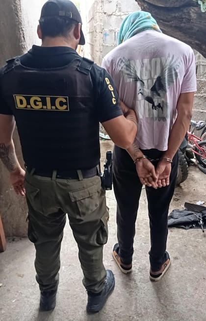Uno de los sospechosos es trasladado esposado durante un procedimiento de la Dirección General de Investigaciones Criminales en barrio Yapeyú, en la ciudad de Córdoba