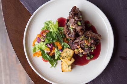 Uno de sus platos insignia llamado Ciudad de los Naranjos: bife de chorizo con costra de morcillas, salsa de naranja amarga, vino tinto y miel riojana.