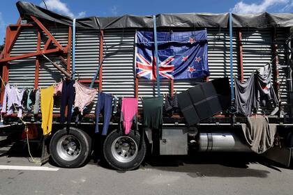 Unos manifestantes cuelgan la ropa en el costado de un camión agrícola adornado con una bandera de Nueva Zelanda, en el noveno día de manifestaciones contra las restricciones de Covid-19 en Wellington el 16 de febrero de 2022, inspiradas por una manifestación similar en Canadá.