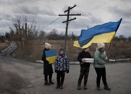 Unos niños recogen donativos para el ejército ucraniano, en una carretera de la región ucraniana de Chernihiv, el domingo 19 de febrero de 2023. 