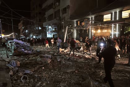 Unos palestinos inspeccionan el lugar donde se produjo un ataque aéreo israelí en Gaza