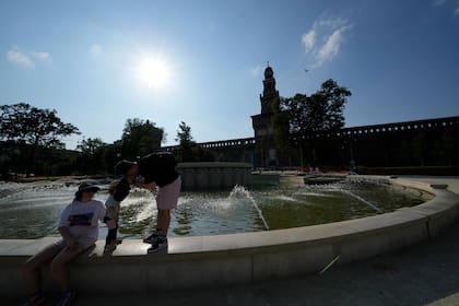 Unos turistas se refrescan en una fuente pública en el castillo Sforzesco en Milán, Italia, en medio de la fuerte ola de calor que azota al sur de Europa.