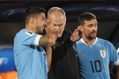Uruguay's coach Marcelo Bielsa, center, gives instructions to Luis Suarez, left, before entering the field during a qualifying soccer match against Bolivia for the FIFA World Cup 2026 at Centenario stadium in Montevideo, Uruguay, Tuesday, Nov. 21, 2023. (AP Photo/Matilde Campodonico)