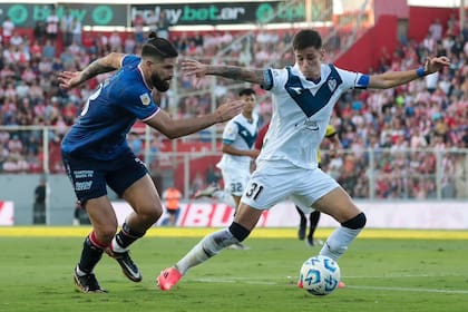 Valentín Gómez, capitán de Vélez, recupera la pelota ante la presión de Nicolás Orsini, delantero de Unión