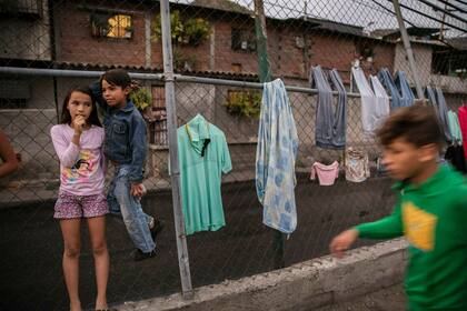 Valentina González, de 10 años, a la izquierda, y su amigo Engleston González, de 8, junto a la ropa secándose en una cerca en Caracas