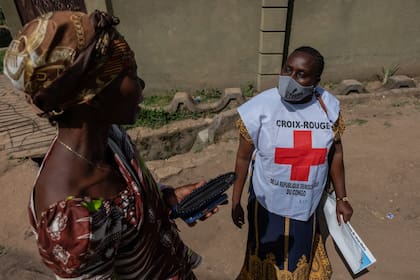 Vanny Birungi, voluntaria de la Cruz Roja, habla con una mujer durante una campaña de sensibilización puerta a puerta en medio del brote de ébola en Bunia, Congo