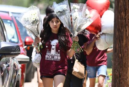 Varias jóvenes llevan flores y globos a la Escuela Primaria Robb, en Uvalde, Texas, el jueves 26 de mayo de 2022, un día después de un tiroteo en el que murieron 19 niños y dos docentes. (Kin Man Hui/The San Antonio Express-News via AP)