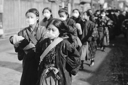 Varias niñas japonesas se cubren el rostro con tapabocas durante la pandemia de la gripe española, a principios del siglo XX