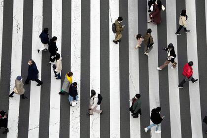 Varias personas caminan por un paso de peatones en Tokio, el 17 de enero de 2022. (AP Foto/Eugene Hoshiko)