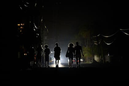 Varias personas caminando en la oscuridad durante un apagón en La Habana, Cuba, el miércoles 28 de mayo de 2025. (AP Foto/Ramón Espinosa)