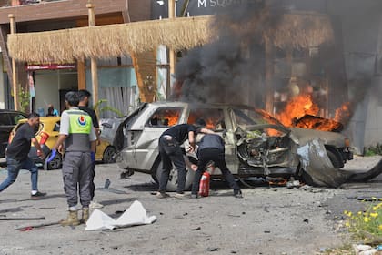 Varias personas intentan apagar un vehículo en llamas tras ser alcanzado por un ataque israelí en la ciudad costera de Barja, al sur de Beirut, Líbano