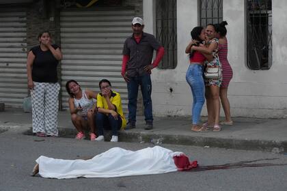 Varias personas lloran junto al cadáver de un hombre, asesinado en circunstancias desconocidas, en una calle de Durán, Ecuador, el 21 de julio de 2023, en medio de una ola de violencia que las autoridades atribuyen a la lucha de territorio entre bandas del crimen organizado.