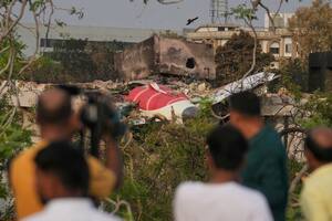 Varias personas observan los restos del avión de Air India que se estrelló contra un edificio, en Ahmedabad, India, el 14 de junio de 2025. (AP Foto/Rafiq Maqbool)