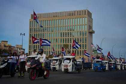 Varias personas pasan en vehículos eléctricos frente a la embajada de Estados Unidos durante una marcha juvenil antiimperialista, el 2 de abril de 2026