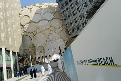 Varias personas pasan junto al Al Wasl Dome de Expo City antes de la Cumbre Climática COP28 de Naciones Unidas, el 28 de noviembre de 2023, en Dubái, Emiratos Árabes Unidos. (AP Foto/Peter Dejong)