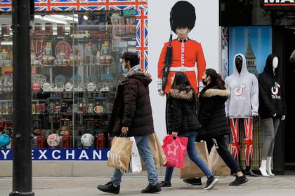 Varias personas que llevan bolsas de compras pasan frente a una tienda de souvenirs en Oxford Street en Londres