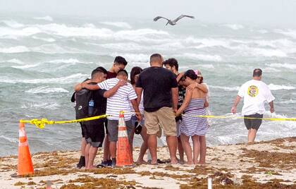 Varias personas se unen para orar en la playa frente al sitio donde  colapsó el edificio Champlain Towers South 