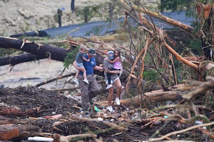 Varias personas trepan por los restos de un puente sobre el río Guadalupe después de que una inundación repentina arrasara el área, el sábado 5 de julio de 2025, en Ingram, Texas. (AP Foto/Julio Cortez)