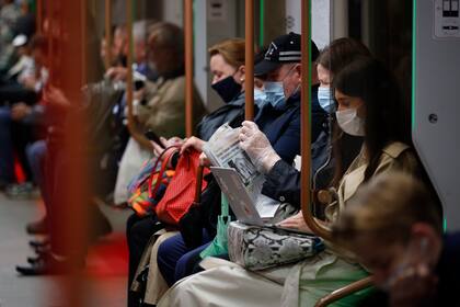 Varias personas vstiendo mascarillas para frenar la propagación del coronavirus viajan en el metro de Moscú