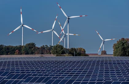 Varias turbinas eólicas giran detrás de una granja solar en Rapshagen, Alemania, el 28 de octubre de 2021