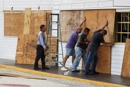 Varios hombres trabajan para proteger una casa antes de la llegada del huracán