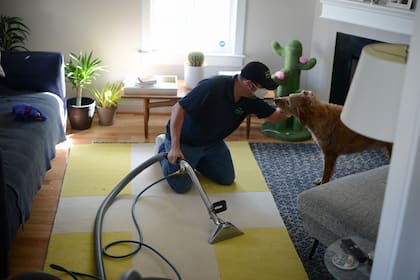 Vaughn Smith, con el perro Schroeder, mientras limpia alfombras en una casa en Virginia