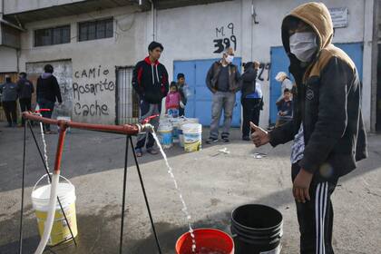 Vecinos de la villa 1-11-14 reciben agua de una camión de Aysa