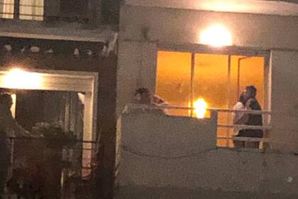 Vecinos se abrazan después de cruzarse a un balcón lindero