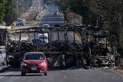 Vehículos pasan junto a un autobús quemado al día siguiente de que el Ejército mexicano matara al Mencho, en Guadalajara, México, el 23 de febrero de 2026