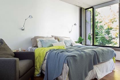 Veladores ‘Tolomeo’ (Iluminación Agüero). En la cama: acolchados individuales verde limón (HAY, Estocolmo) y pie de cama tejido ($4.000, Ramos Generales). Sillón (La Decorería)
