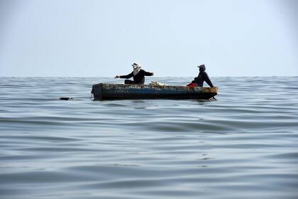 Pescadores navegan el lago altamente contaminado.