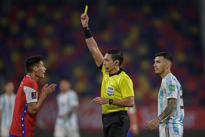 Venezuelan referee Jesus Valenzuela shows the yellow card to Chile's Pablo Galdames as he conducts the South American qualification football match for the FIFA World Cup Qatar 2022 between Argentina and Chile at the Estadio Unico Madre de Ciudades stadium in Santiago del Estero, Argentina, on June 3, 2021. (Photo by Juan Mabromata / POOL / AFP)